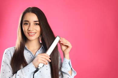 Happy woman using hair iron on color background. Space for text