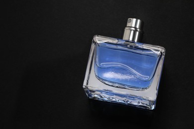 Photo of Blue men's perfume in bottle on black background, top view. Space for text