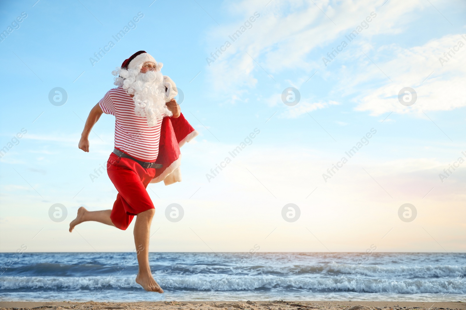 Photo of Santa Claus having fun on beach, space for text. Christmas vacation