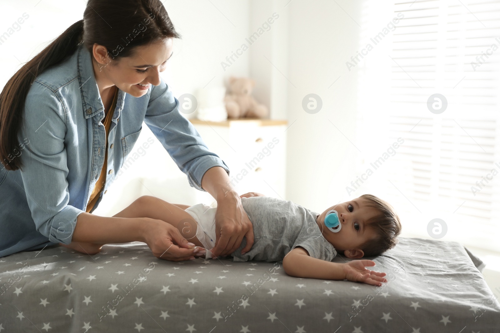 Photo of Mother changing baby's diaper on table at home