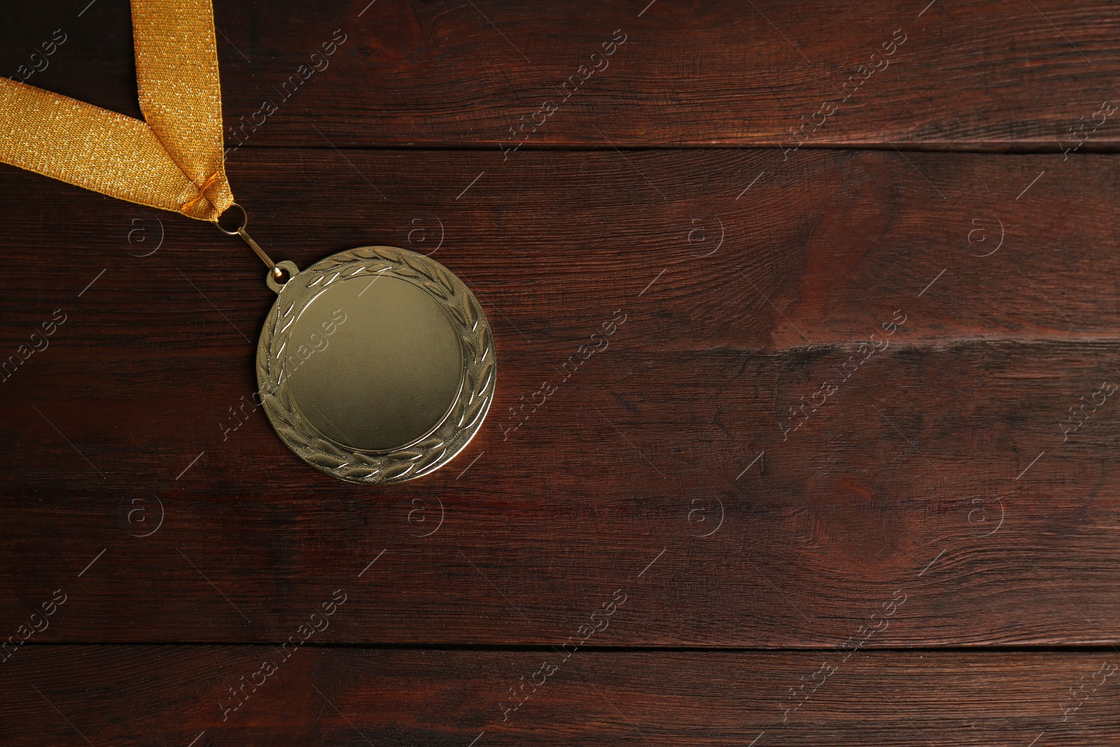 Photo of Gold medal on wooden background, top view. Space for design