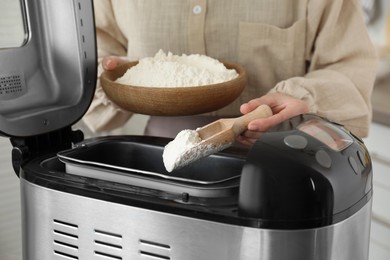 Photo of Making dough. Woman adding flour into breadmaker machine, closeup