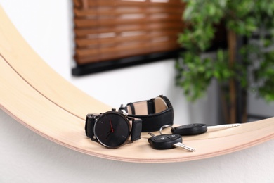 Photo of Stylish round mirror with male accessories on white wall indoors. Interior design