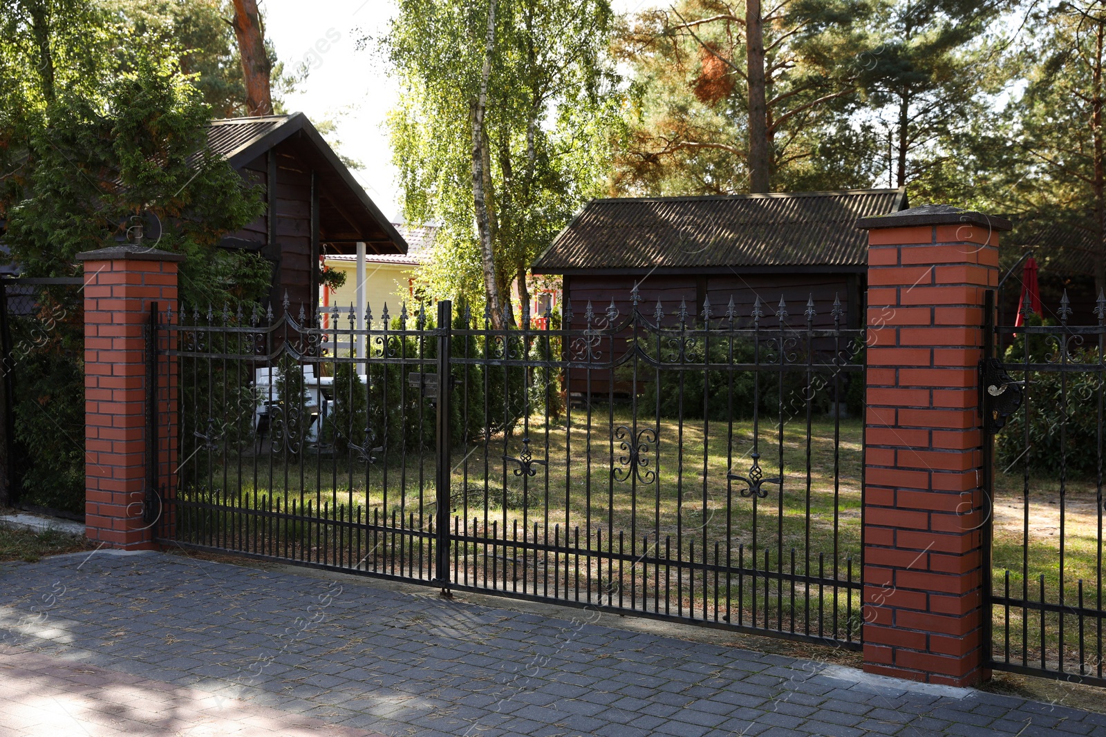 Photo of Metal gates near houses and trees on sunny day