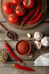 Photo of Red curry paste in bowl and ingredients on wooden table, flat lay