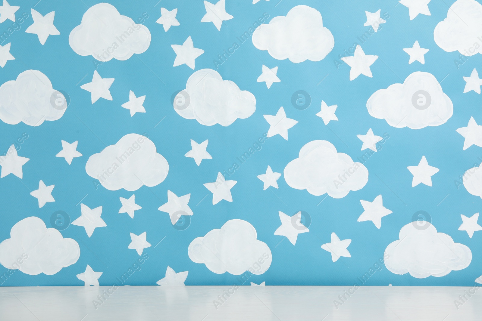 Photo of White table near wall with painted blue sky. Idea for baby room interior