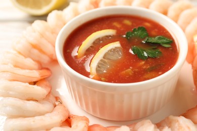 Photo of Tasty boiled shrimps with cocktail sauce and lemon on plate, closeup