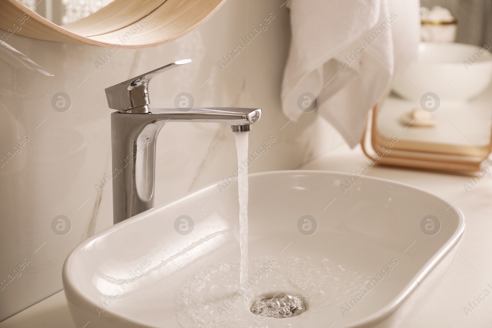 Photo of Sink with running water in stylish bathroom interior