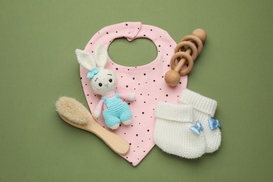 Flat lay composition with baby accessories and bib on green background