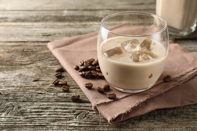 Coffee cream liqueur in glass and beans on wooden table, space for text