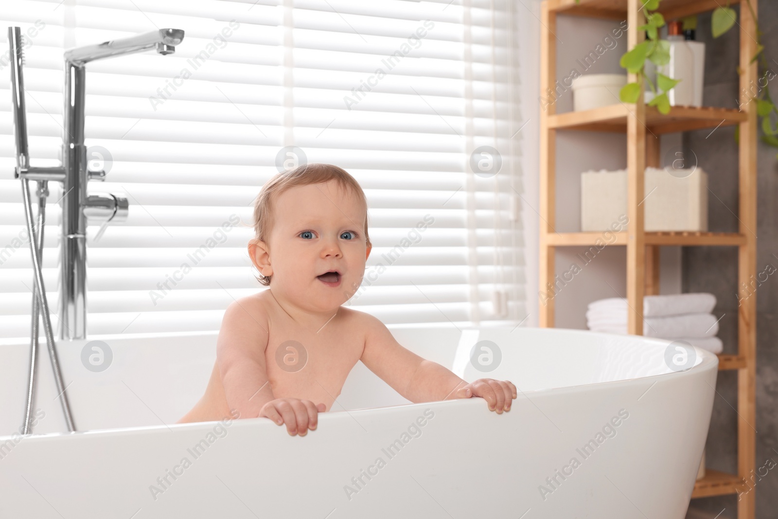 Photo of Cute little baby bathing in tub at home