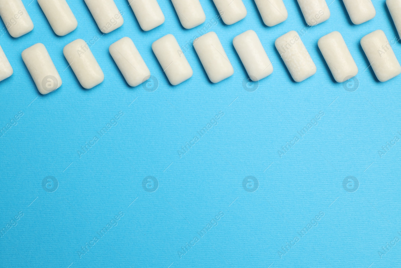 Photo of White bubble gums on blue background, flat lay. Space for text