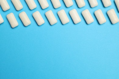 White bubble gums on blue background, flat lay. Space for text