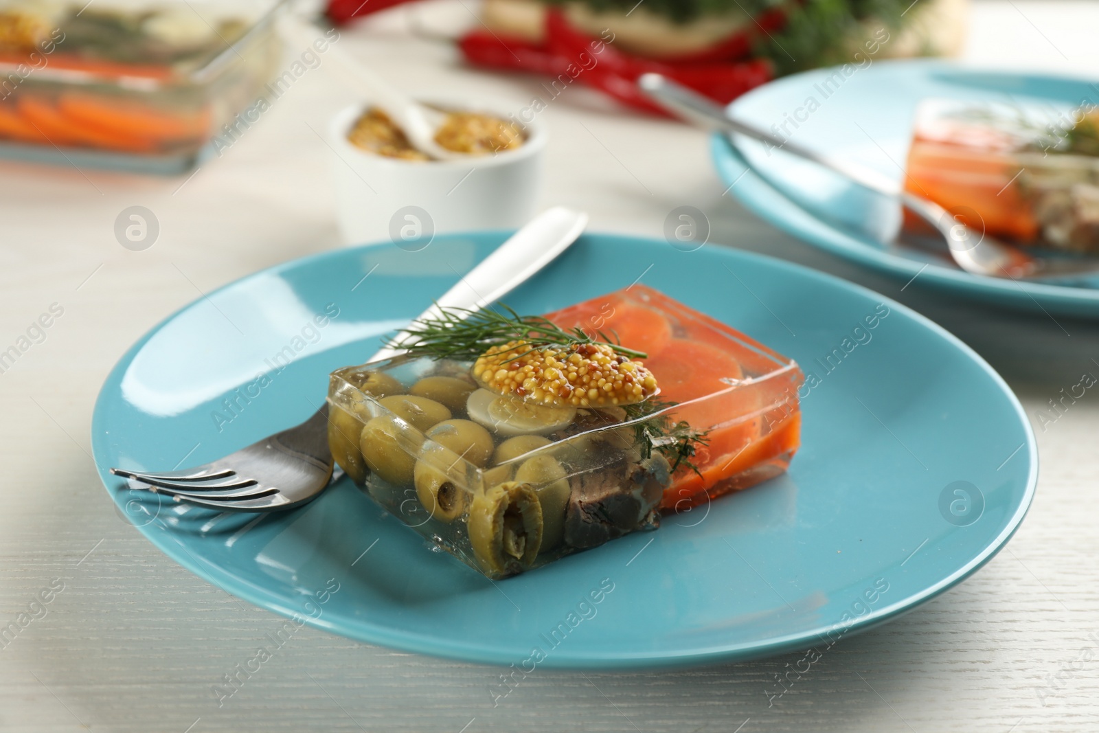 Photo of Plate with delicious aspic on white wooden table