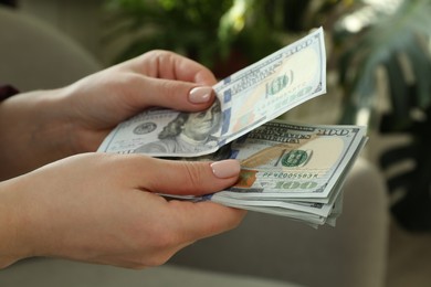 Photo of Money exchange. Woman counting dollar banknotes on blurred background, closeup