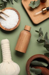 Photo of Different aromatherapy products and eucalyptus leaves on olive background, flat lay