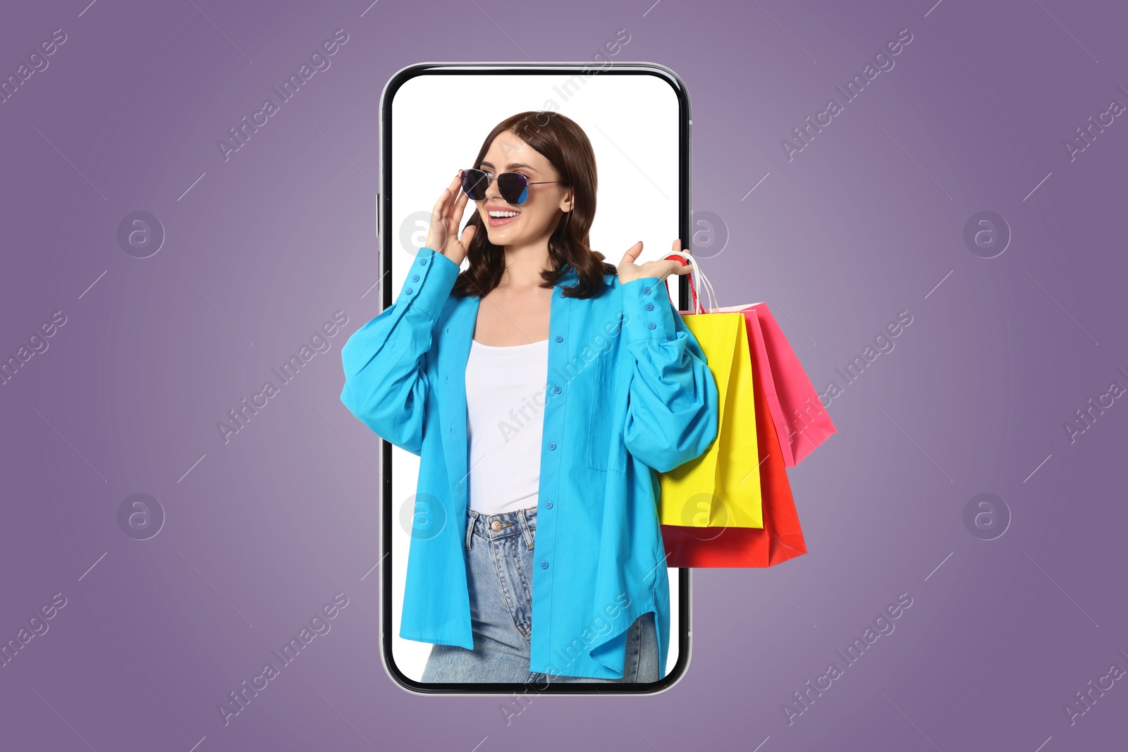 Image of Online shopping. Happy woman with paper bags looking out from smartphone on violet background