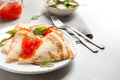 Thin pancakes served with red caviar on plate