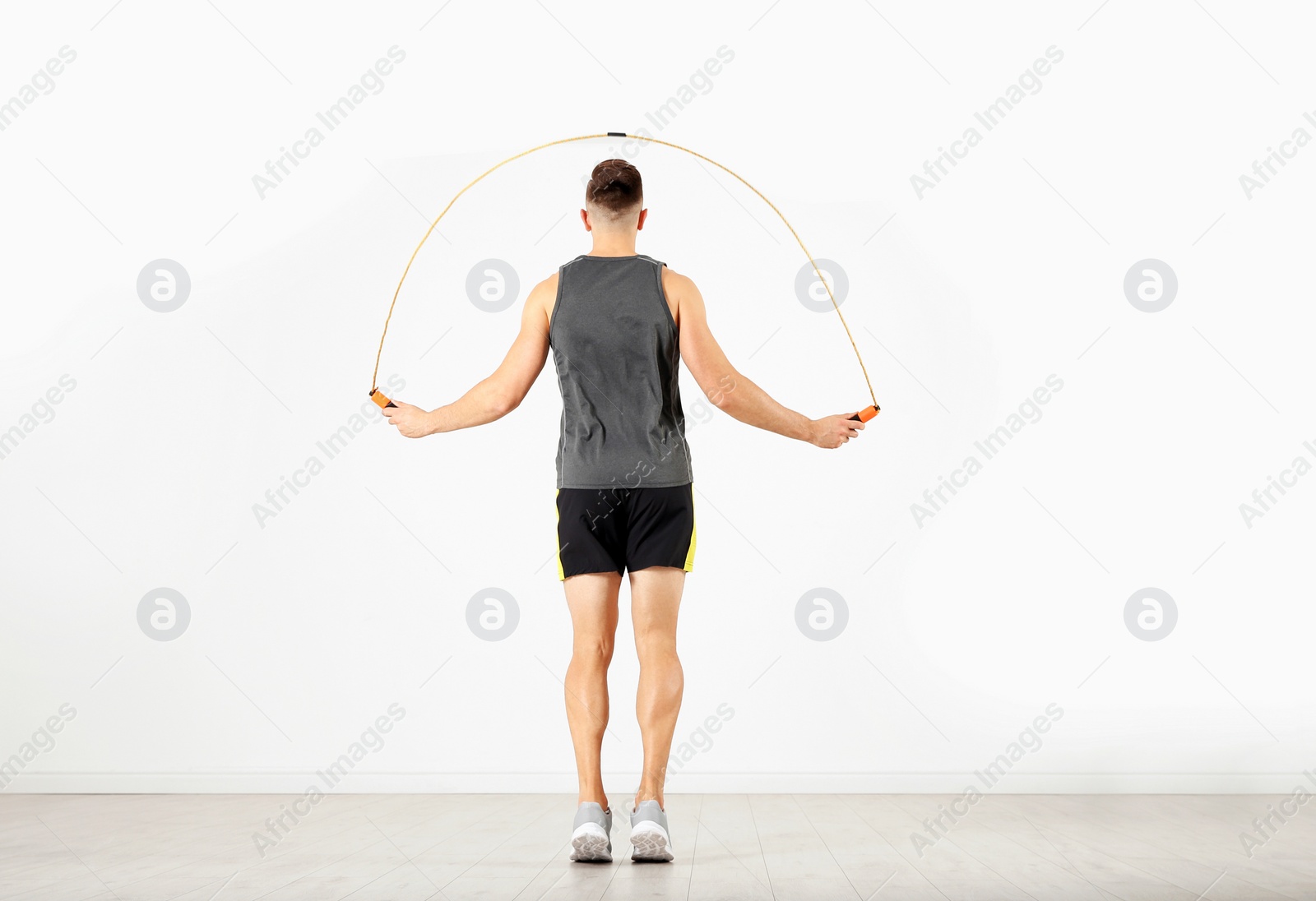 Photo of Sportive man training with jump rope in light room