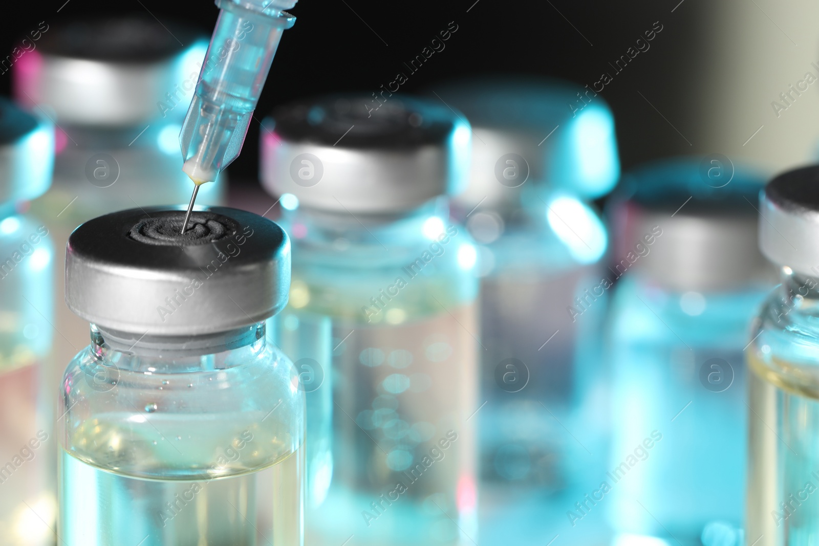 Photo of Filling syringe with medicine from vial against blurred background, closeup