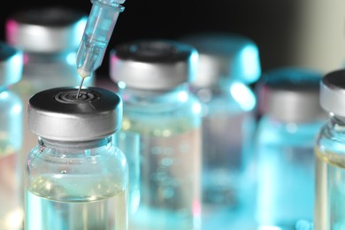 Filling syringe with medicine from vial against blurred background, closeup