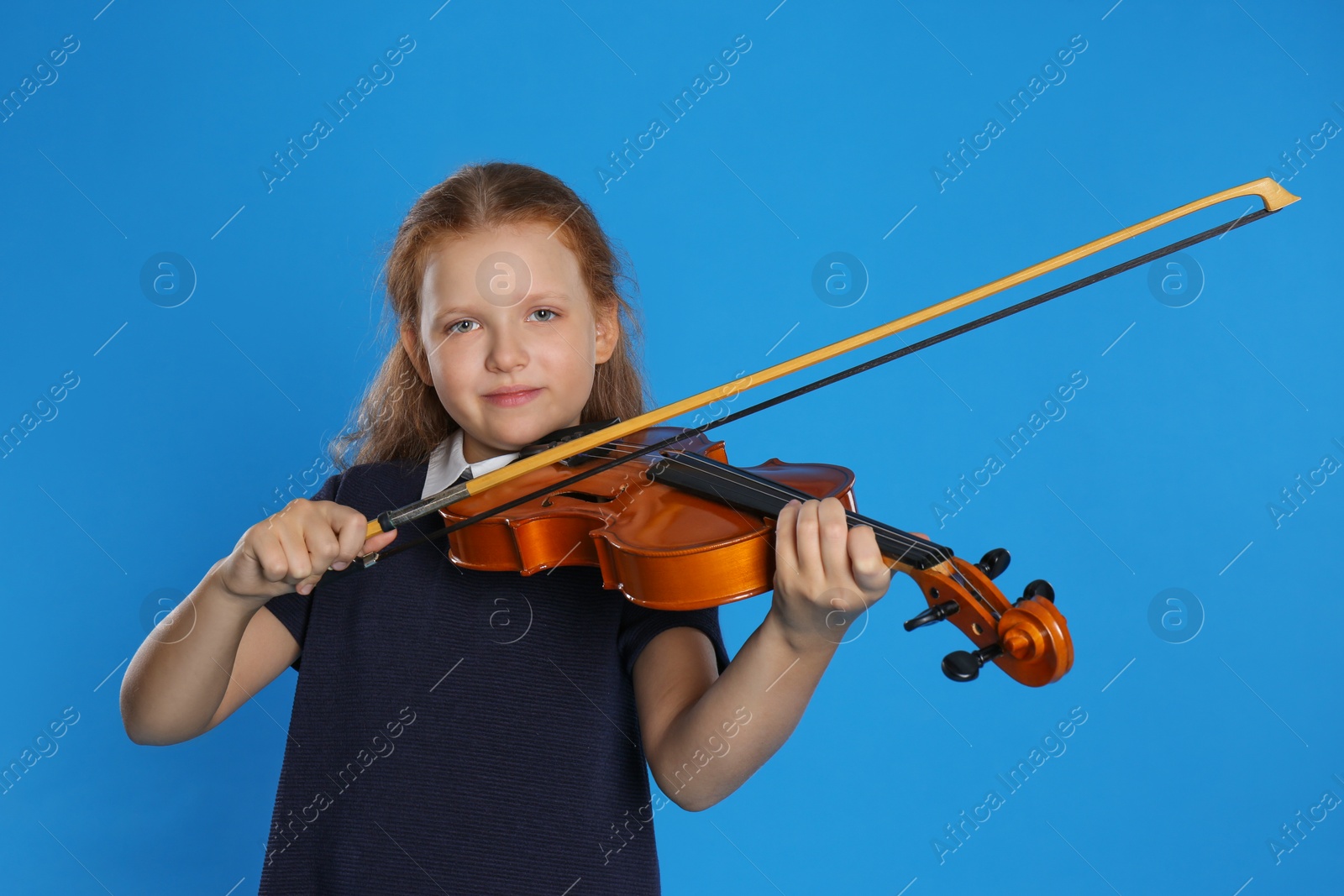 Photo of Preteen girl playing violin on light blue background