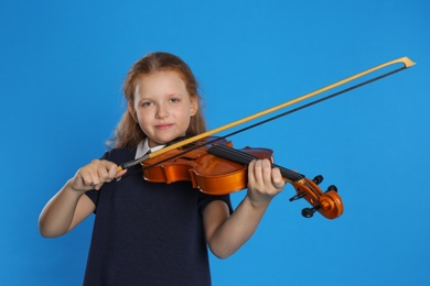 Photo of Preteen girl playing violin on light blue background