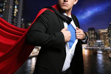 Image of Closeup view of businessman wearing superhero costume and beautiful cityscape in night on background