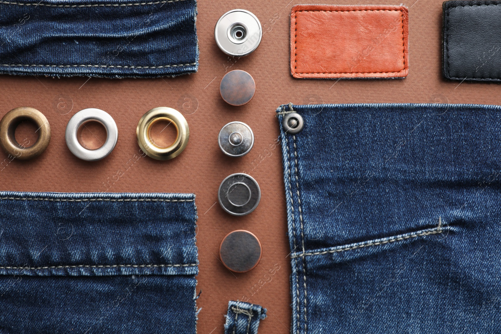 Photo of Flat lay composition with garment accessories and cutting details for jeans on brown background