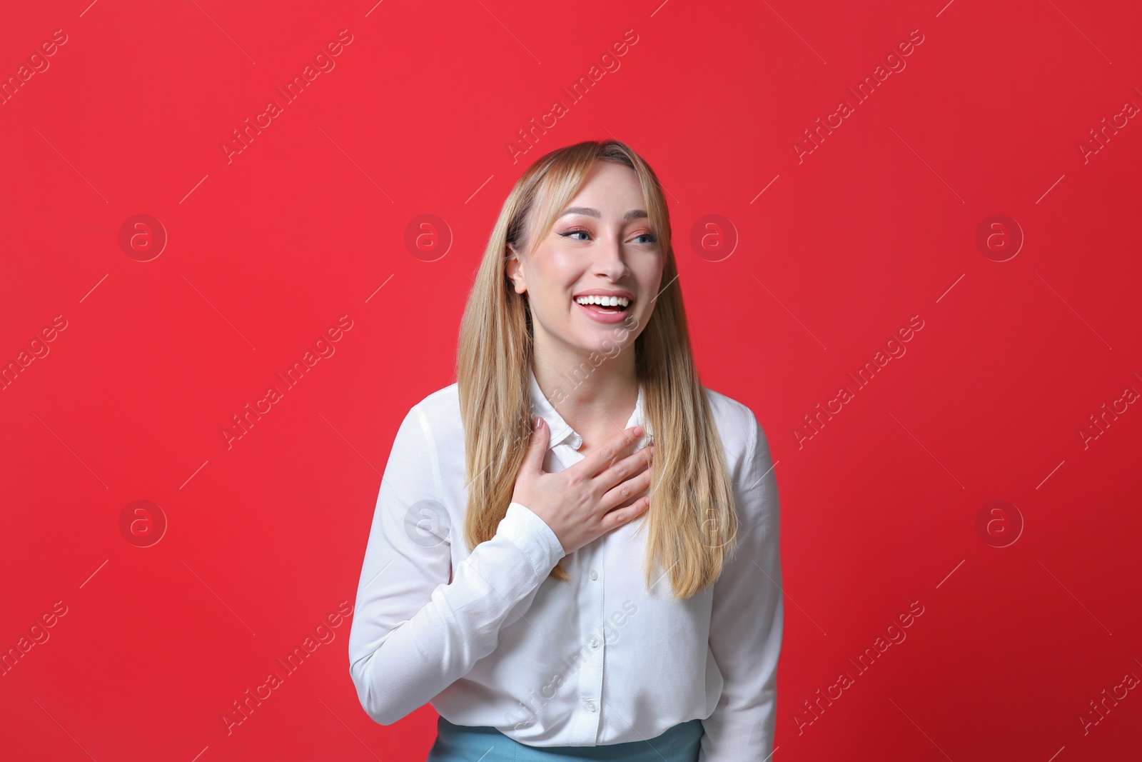 Photo of Beautiful young woman laughing on red background. Funny joke