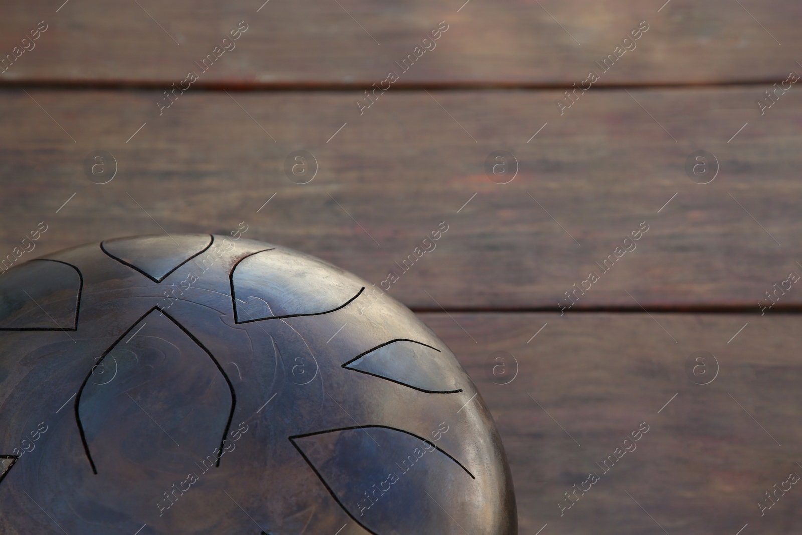 Photo of Steel tongue drum on wooden table, closeup. Space for text. Percussion musical instrument