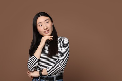 Portrait of smiling woman on brown background. Space for text