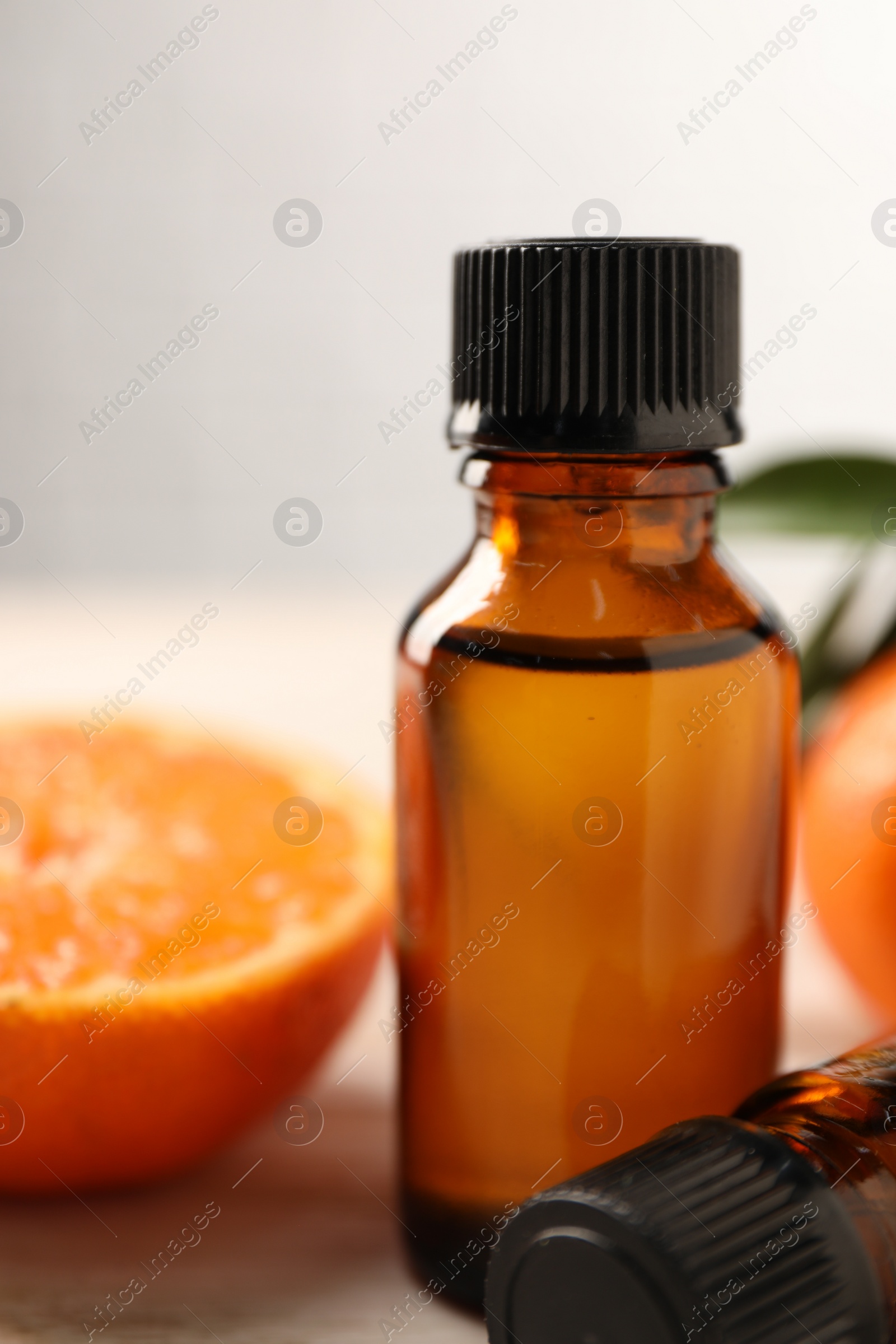 Photo of Bottles of tangerine essential oil and fresh fruits on wooden table, closeup