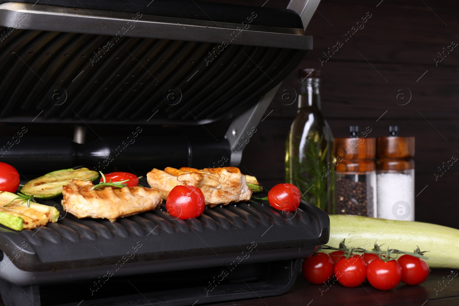 Photo of Electric grill with different products on wooden table