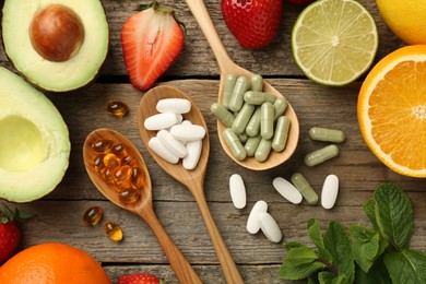 Photo of Different vitamin pills and fresh fruits on old wooden table, flat lay