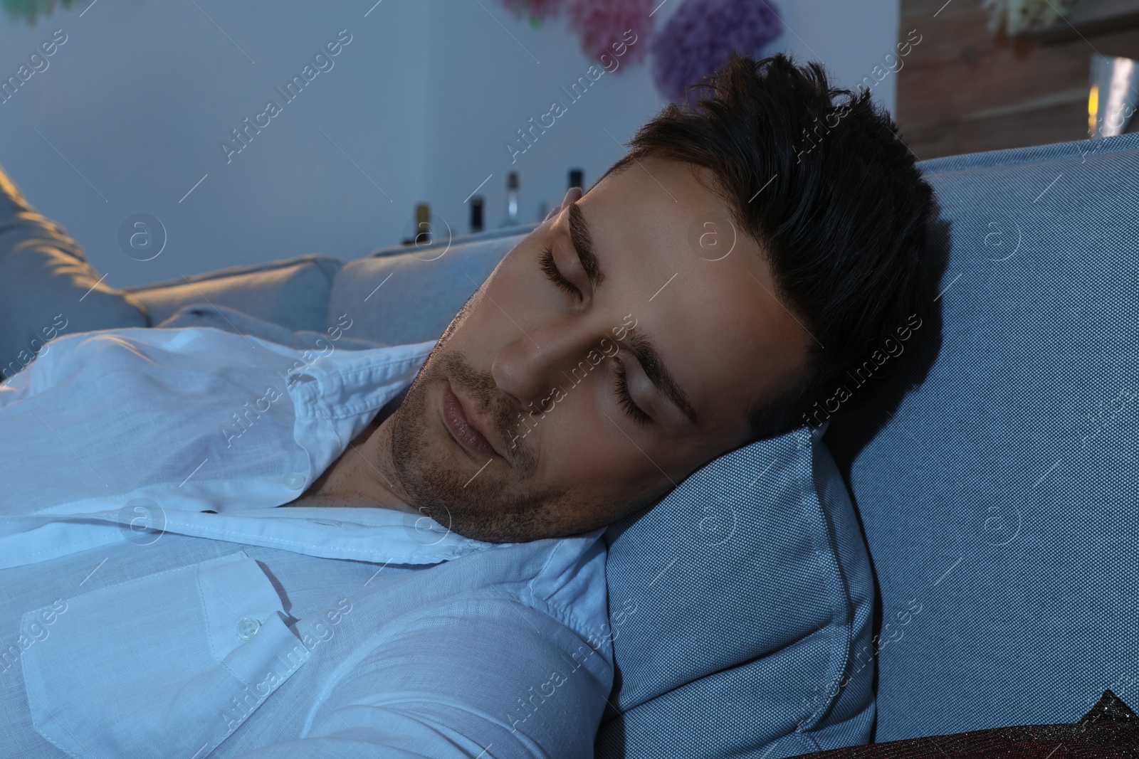 Photo of Young man sleeping on sofa in room after party