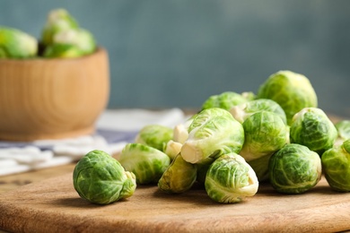 Photo of Fresh Brussels sprouts on wooden board, closeup