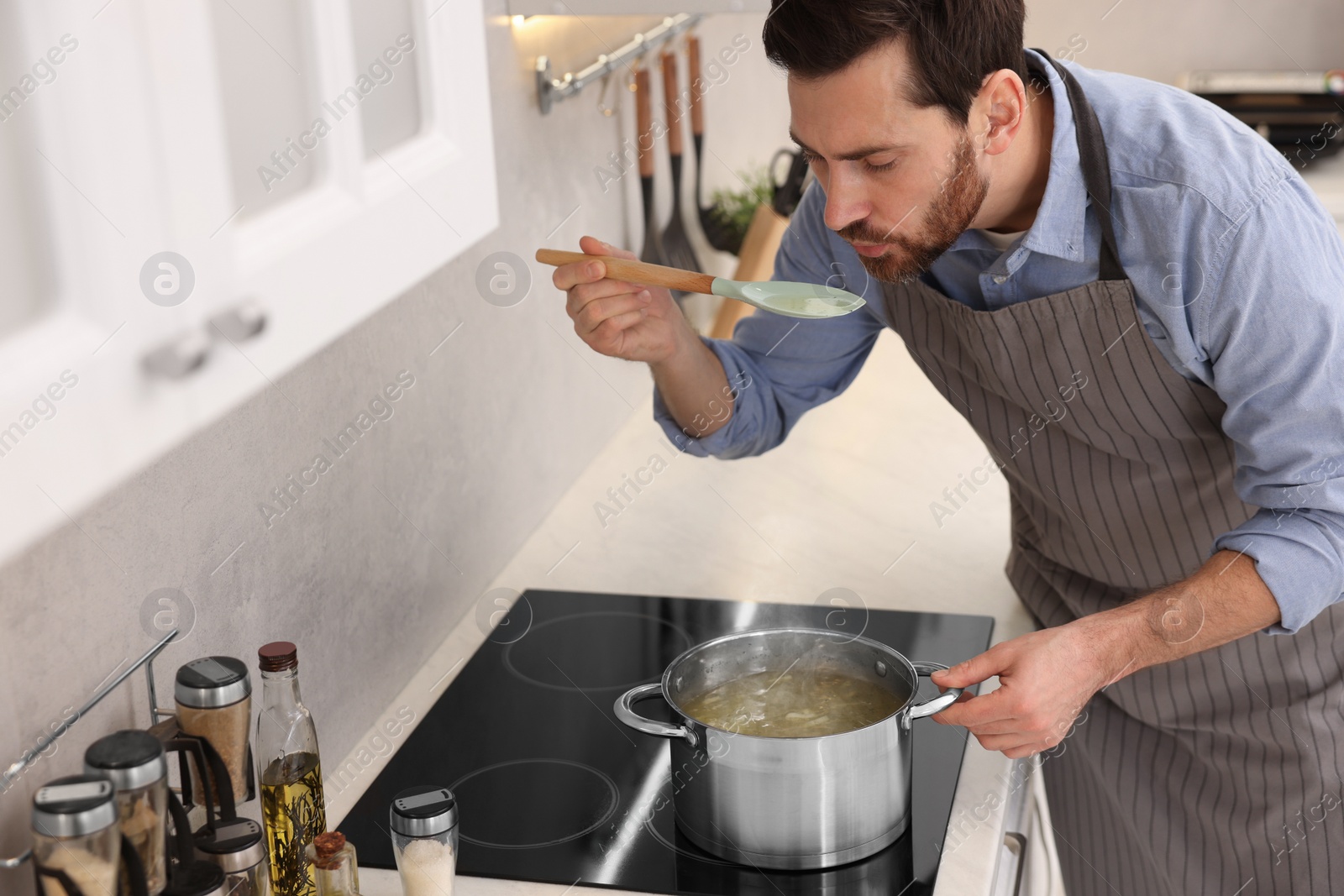 Photo of Man tasting delicious chicken soup in kitchen