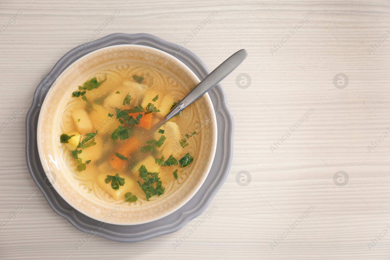 Photo of Bowl with delicious hot broth on wooden background, top view. Cold treatment