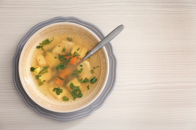 Photo of Bowl with delicious hot broth on wooden background, top view. Cold treatment