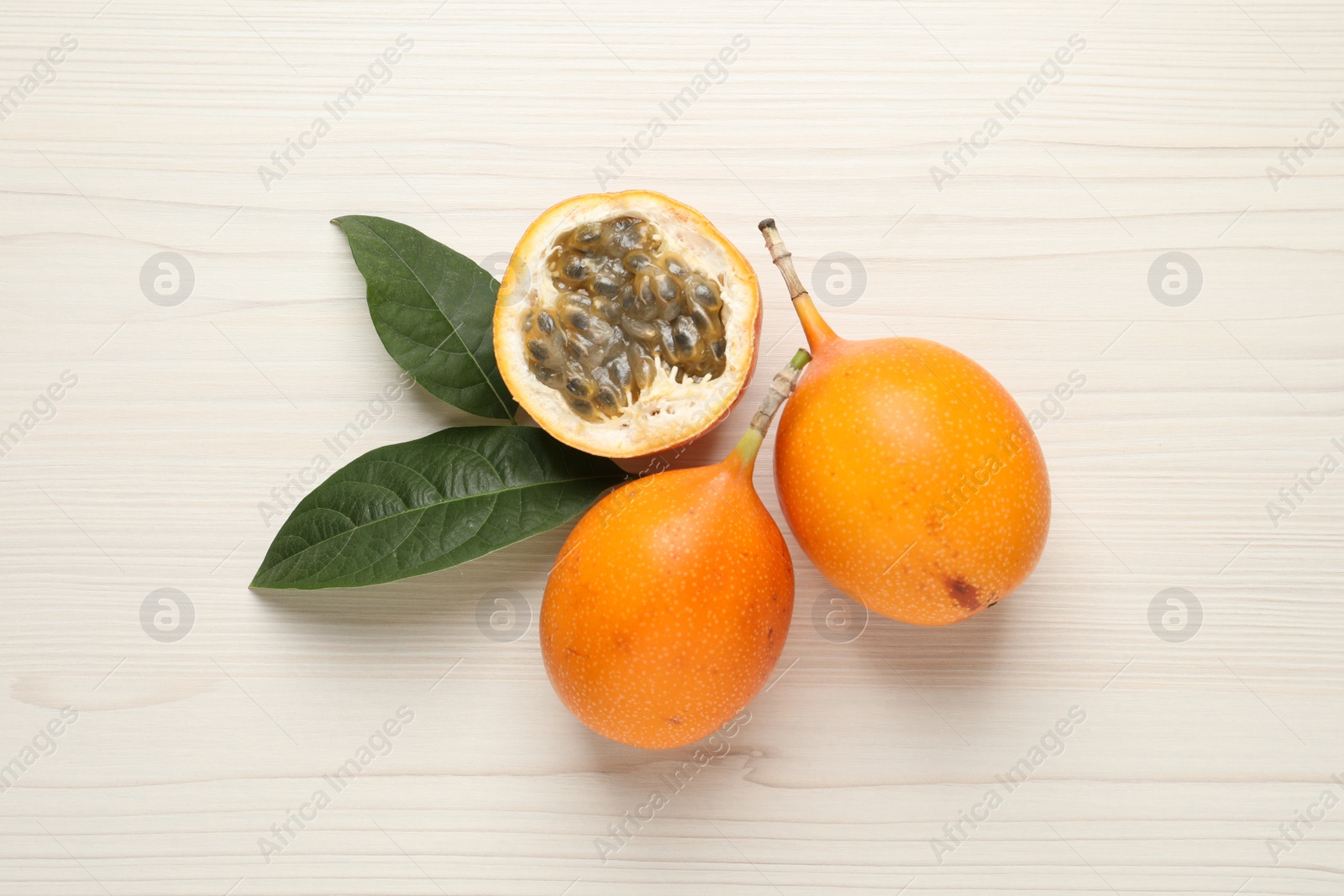 Photo of Delicious ripe granadillas on white wooden table, flat lay