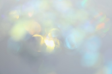 Blurred view of shiny lights on light background. Bokeh effect