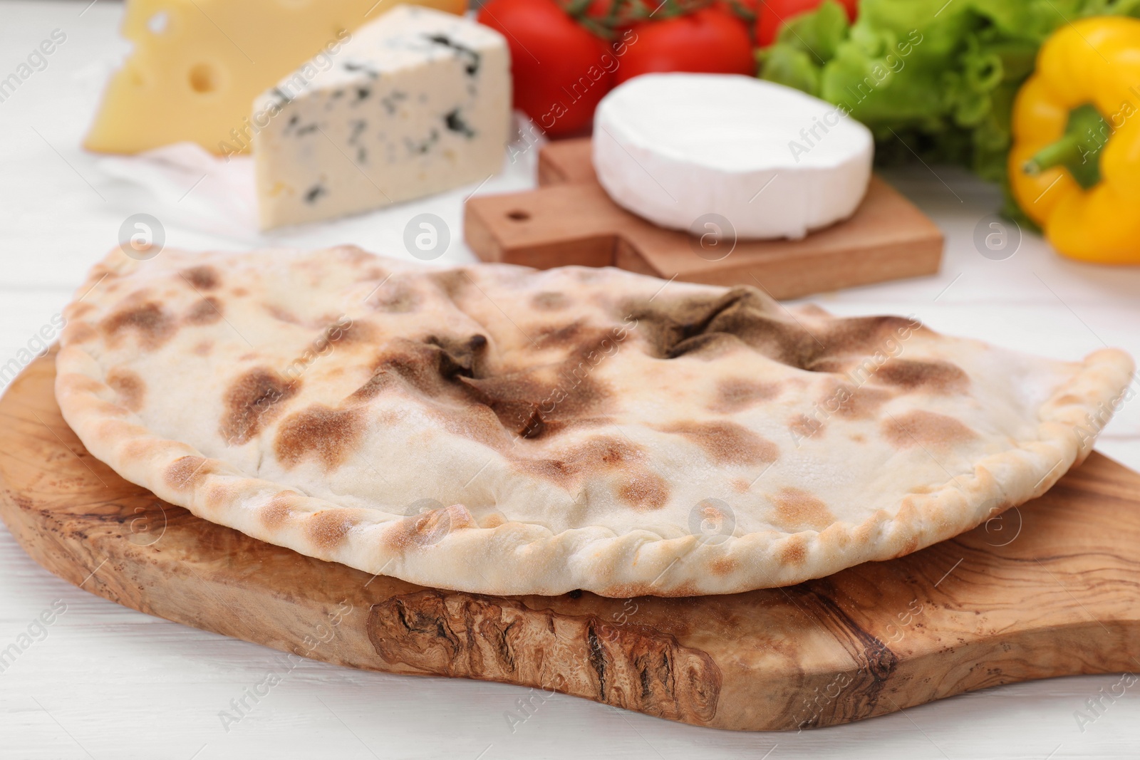 Photo of Delicious cheese calzone on white wooden table, closeup