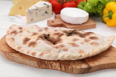 Delicious cheese calzone on white wooden table, closeup