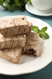 Photo of Pieces of tasty chocolate halva and mint on table, closeup