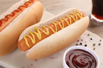 Photo of Tasty hot dogs with mustard and ketchup on board, closeup