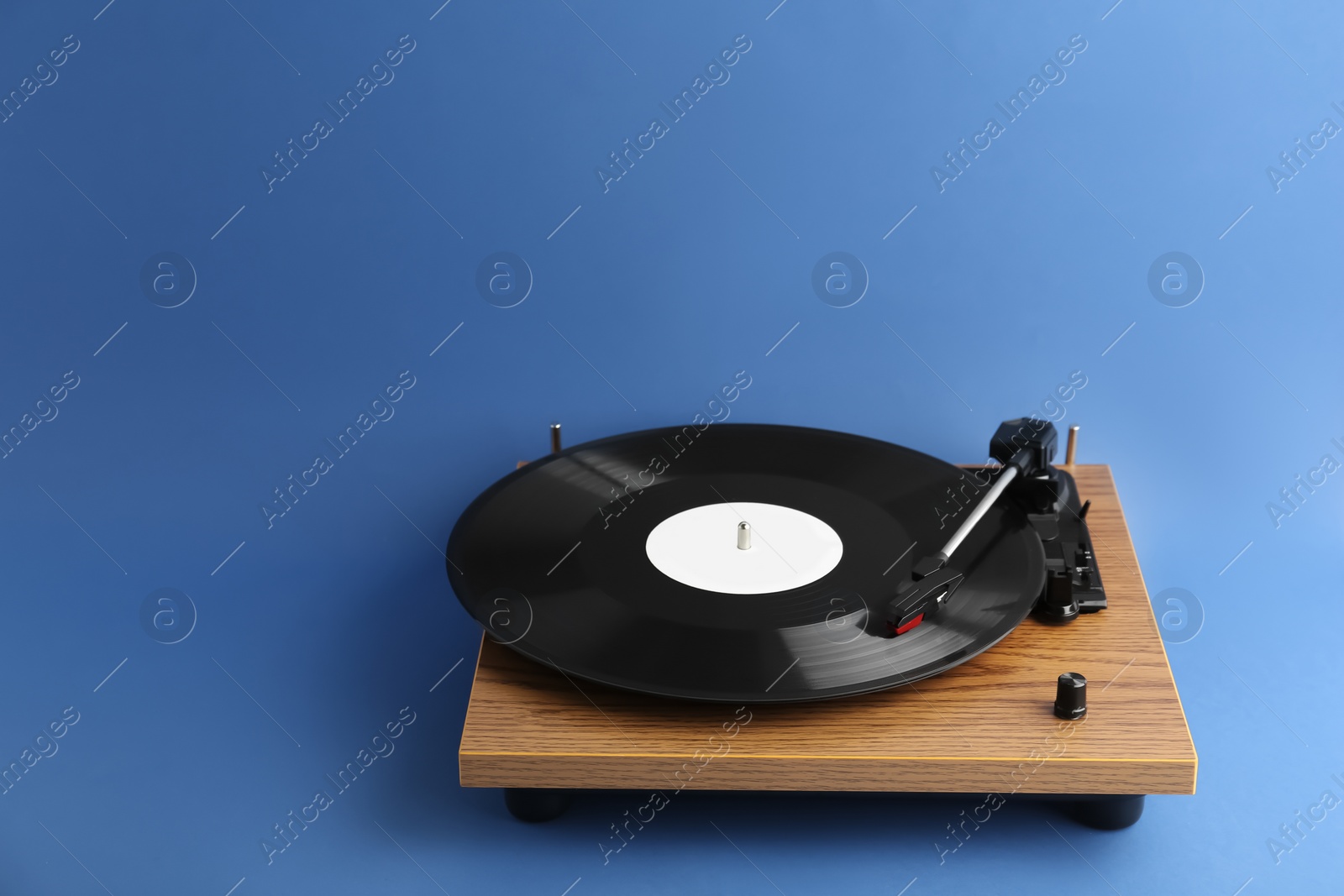 Photo of Turntable with vinyl record on blue background. Space for text