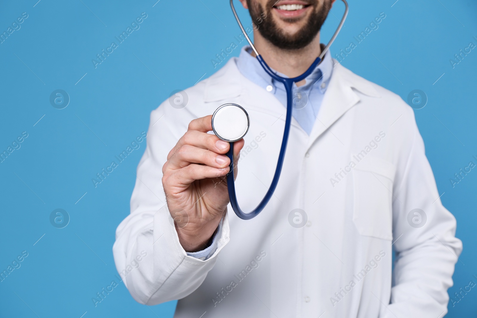 Photo of Doctor with stethoscope on light blue background, closeup. Cardiology concept