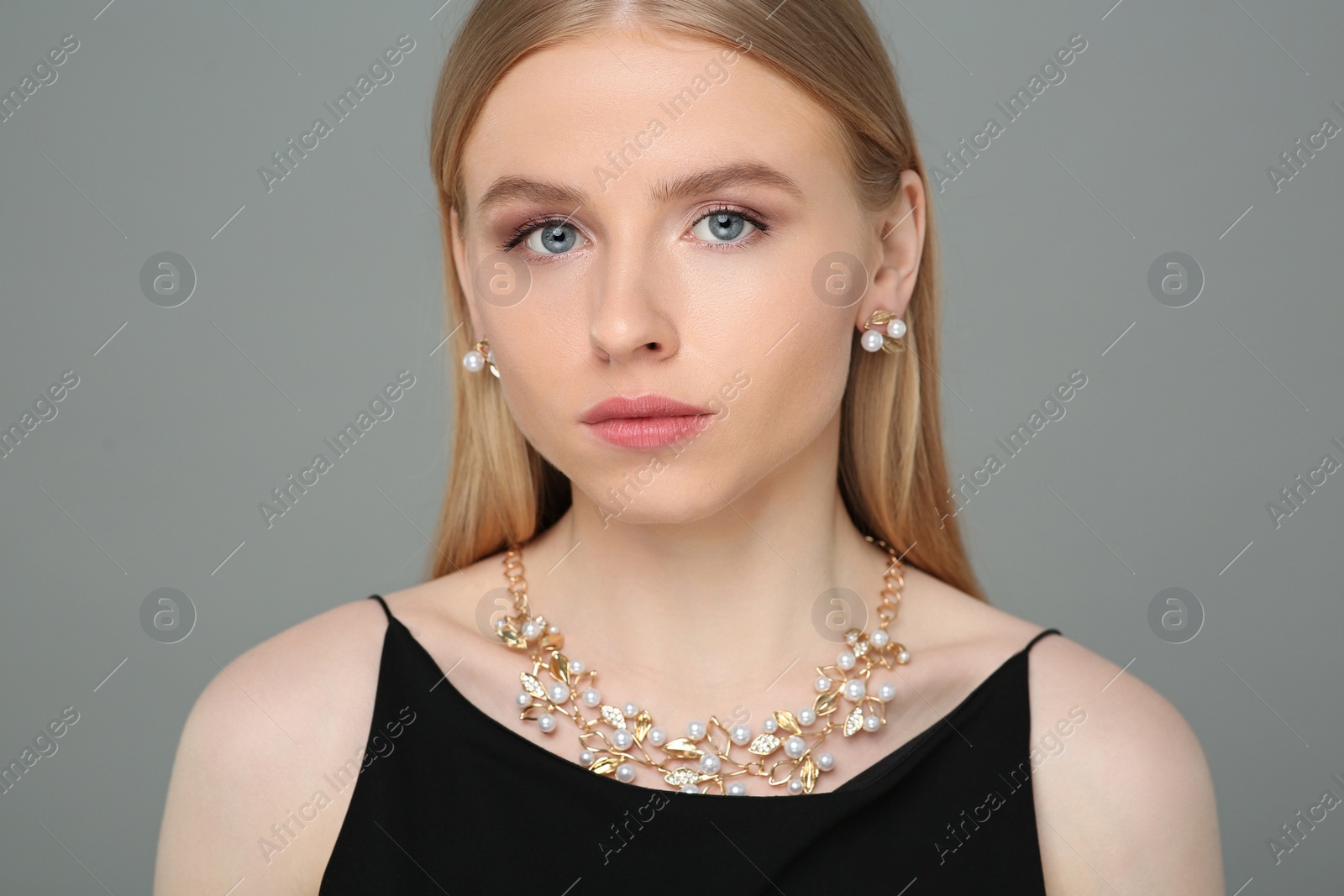 Photo of Beautiful young woman with elegant jewelry on gray background