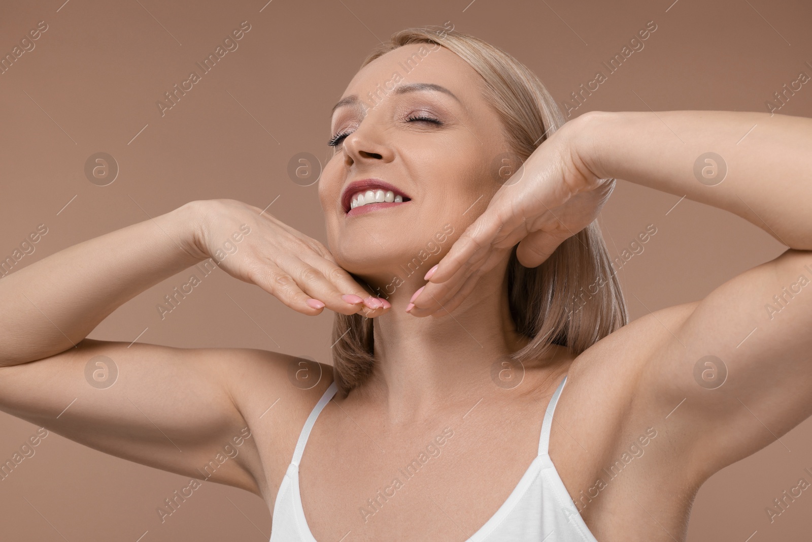 Photo of Beautiful woman touching her neck on beige background